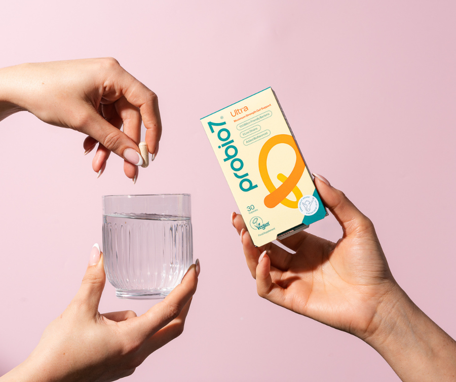 Hands holding Probio7 Ultra and a glass of water. 